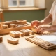 Klein kind ordent houten Montessori-materialen op eikenhouten tafel naast open curriculum­map, warm ochtendlicht door schoolramen.